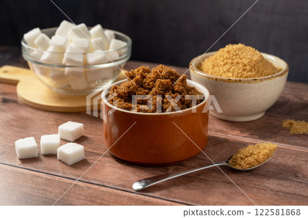 Different type of sugar, light brown, dark brown and white sugar cubes in bowls. Different type of sugar, light brown, dark brown and white sugar cubes in bowls. 122581868