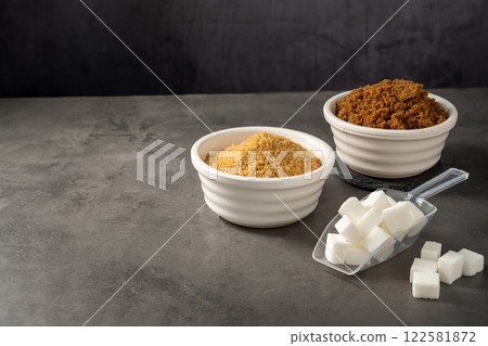Different type of sugar, light brown, dark brown and white sugar cubes in bowls.  122581872