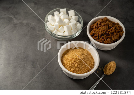 Different type of sugar, light brown, dark brown and white sugar cubes in bowls. Different type of sugar, light brown, dark brown and white sugar cubes in bowls. 122581874