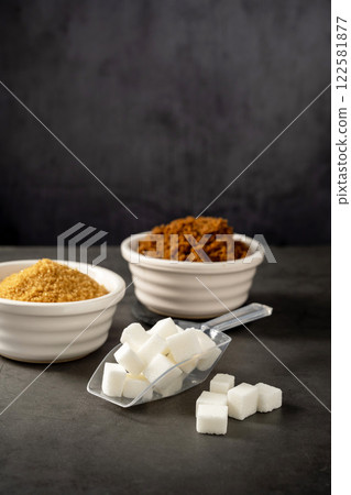 Different type of sugar, light brown, dark brown and white sugar cubes in bowls.  122581877