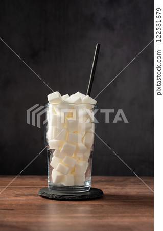 Sugar addiction. Glass full of white sugar cubes - unhealthy diet concept. 122581879