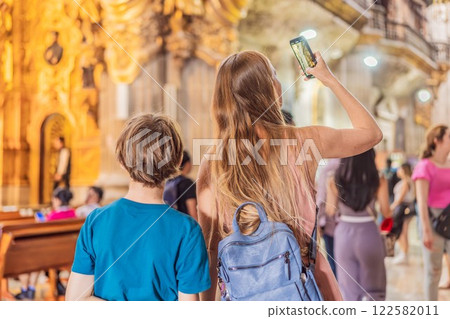 A woman and her son tourists exploring the Metropolitan Cathedral in Mexico City. Woman admiring the architecture and history of Mexico's iconic landmark. Concept of cultural heritage, religious A woman and her son tourists exploring the Metropolitan Cathedral in Mexico City. Woman admiring the architecture and history of Mexico's iconic landmark. Concept of cultural heritage, religious 122582011