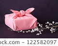 A furoshiki wrapping cloth and a cherry blossom branch on a purple cloth 122582097