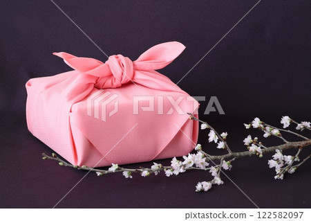 A furoshiki wrapping cloth and a cherry blossom branch on a purple cloth 122582097
