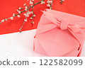 Pink furoshiki wrapping and cherry blossom branch placed on red and white washi paper 122582099