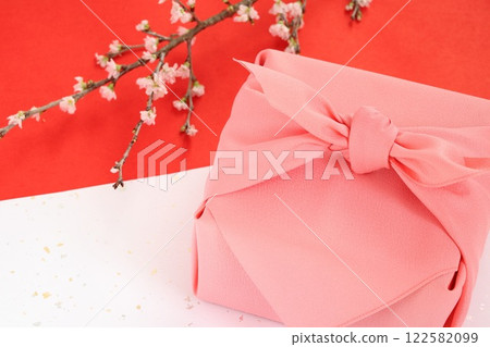 Pink furoshiki wrapping and cherry blossom branch placed on red and white washi paper Pink furoshiki wrapping and cherry blossom branch placed on red and white washi paper 122582099