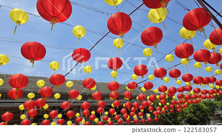 Vibrant red and yellow lanterns suspended across open balconies under a serene blue sky, representing festive celebrations of chinese new year and traditional cultural decor 122583057
