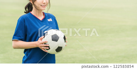 A Japanese woman who is a fan supporter playing soccer with a smile while holding a soccer ball A Japanese woman who is a fan supporter playing soccer with a smile while holding a soccer ball 122583854