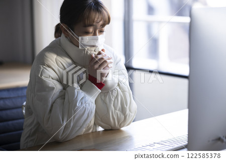 A woman working while feeling cold 122585378