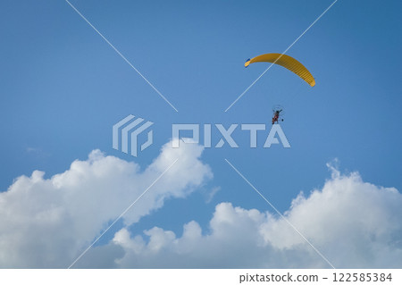 Paramotor flying in blue sky. Paramotor flying in blue sky. 122585384