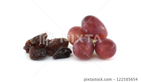 Close-up of a small bunch of red grapes next to a pile of dark, plump raisins Close-up of a small bunch of red grapes next to a pile of dark, plump raisins 122585654
