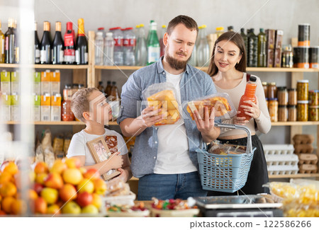 Young family with little son holding products in supermarket 122586266