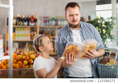 Young dad and tween son choosing packaged chicken in supermarket Young dad and tween son choosing packaged chicken in supermarket 122586271
