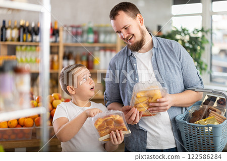 Young dad and tween son choosing packaged chicken in supermarket Young dad and tween son choosing packaged chicken in supermarket 122586284