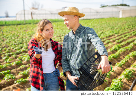 Female gardener discussing spring works with husband on field 122586415