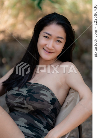 Portrait of sexy asian woman in a military print strapless dress, camping in the forest concept. 122586430