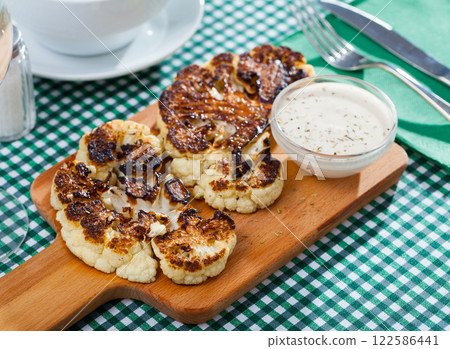 Grilled cauliflower on wooden cutting board Grilled cauliflower on wooden cutting board 122586441