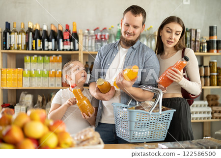 Young family with little son choosing natural juice in supermarket 122586500