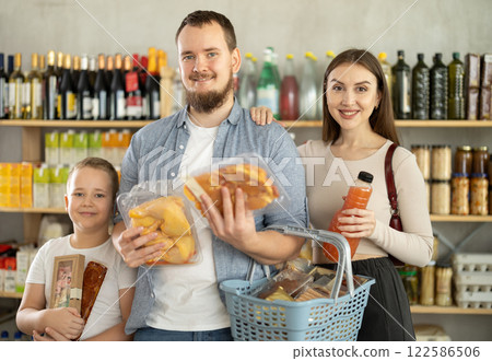 Young family with little son holding products in supermarket Young family with little son holding products in supermarket 122586506