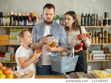 Young family with little son scanning QR on bottle of juice in supermarket Young family with little son scanning QR on bottle of juice in supermarket 122586507