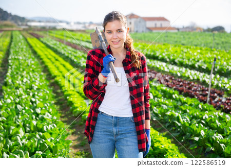 Smiling young girl working on vegetable beds of farm Smiling young girl working on vegetable beds of farm 122586519