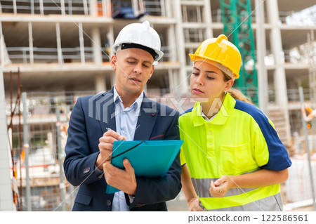 Civil engineer and a young woman worker discuss a construction plan Civil engineer and a young woman worker discuss a construction plan 122586561