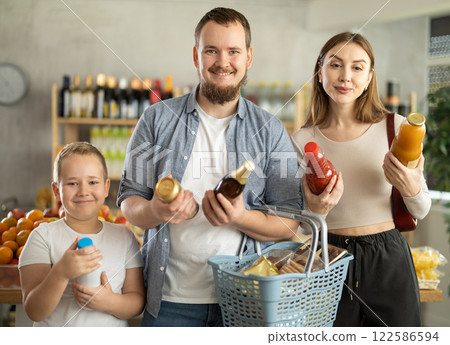 Positive family with little son choosing drinks in supermarket Positive family with little son choosing drinks in supermarket 122586594