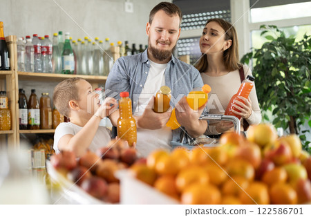 Couple of man and woman with boy choosing juices in grocery 122586701