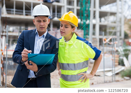 Civil engineer and a young woman worker discuss a construction plan 122586720