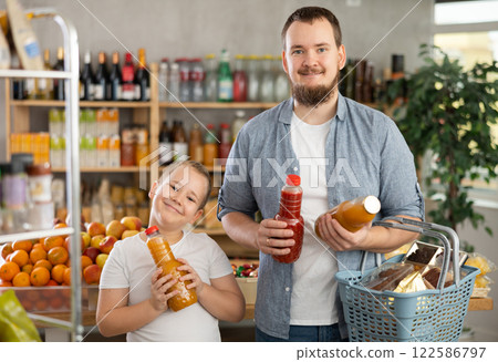 Man with son hold packages plastic bottle and choose consider fruit juice in store 122586797