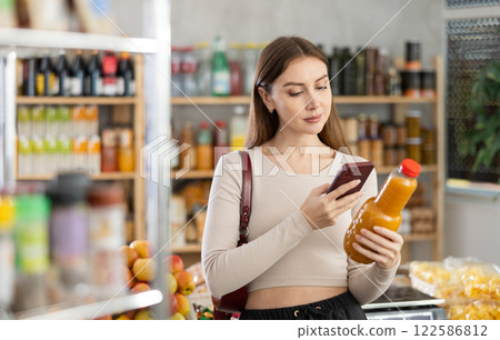 Young woman scanning qr code of peach juice Young woman scanning qr code of peach juice 122586812