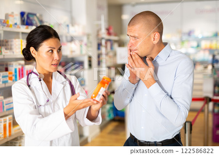 Female pharmacist helping man with toothache in drugstore Female pharmacist helping man with toothache in drugstore 122586822