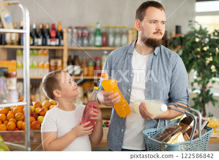 Preteen boy with father choosing sweet beverages in grocery store Preteen boy with father choosing sweet beverages in grocery store 122586842