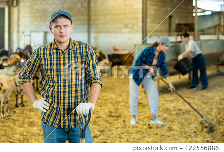 Farmer does the cleaning in goat shed Farmer does the cleaning in goat shed 122586886