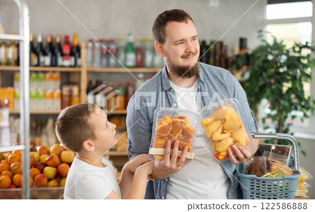 Man with son holding plastic containers with poultry parts, choose chicken meat. 122586888