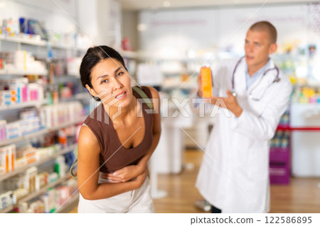 Woman complains to a pharmacist about a sore belly. Help in choosing a medicine in pharmacy 122586895