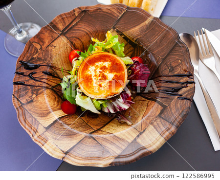 Fried goat cheese salad with vegetables, greens, nuts and raisins 122586995