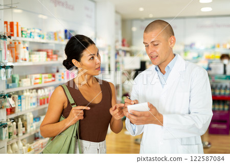 Pharmacist writing recipe for woman in drugstore 122587084