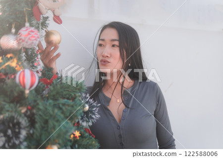 Beautiful Asian woman poses cutely with Christmas tree. Beautiful Asian woman poses cutely with Christmas tree. 122588006