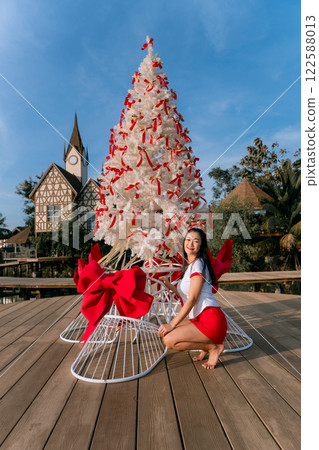 Beautiful Asian woman poses cutely with Christmas tree. Beautiful Asian woman poses cutely with Christmas tree. 122588013