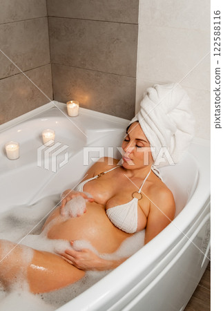 Pregnant Woman Relaxing in Bubble Bath with Candles 122588116