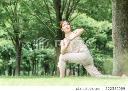 Young Asian woman doing park yoga, yoga, pilates, stretching in forest/park 122589069