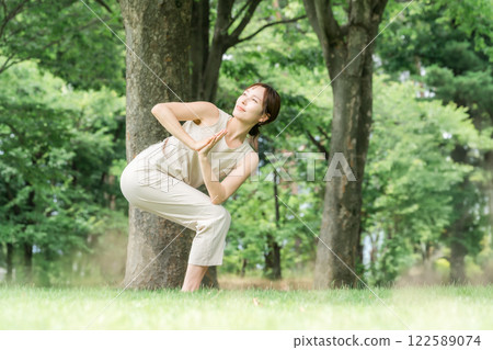 Young Asian woman doing park yoga, yoga, pilates, stretching in forest/park 122589074