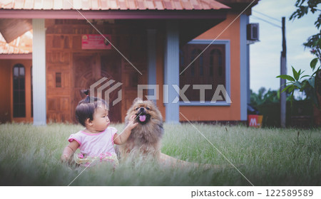Baby asian girl Play with fun in the grass in front of the house. happily Baby asian girl Play with fun in the grass in front of the house. happily 122589589