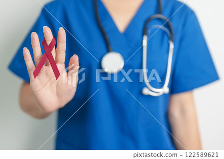 Doctor with Burgundy Red Ribbon for March multiple myeloma Cancer and December World Aids Day Awareness month. Healthcare and world cancer day concept 122589621
