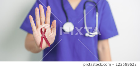 Doctor with Burgundy Red Ribbon for March multiple myeloma Cancer and December World Aids Day Awareness month. Healthcare and world cancer day concept 122589622