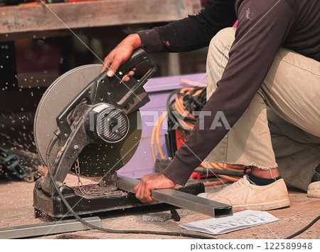 Worker using a sliding compound mitre saw with circular blade for cutting steel metal. Worker using a sliding compound mitre saw with circular blade for cutting steel metal. 122589948