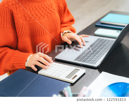 Woman working on desk with calculator and laptop Woman working on desk with calculator and laptop 122591813