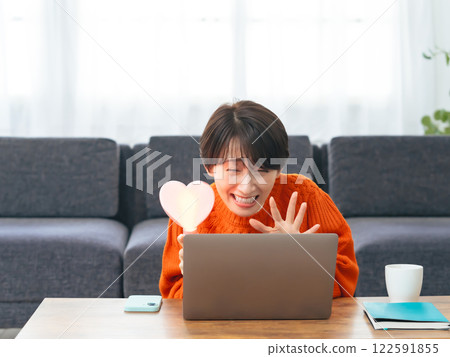 A middle-aged woman watching a live broadcast on her laptop computer A middle-aged woman watching a live broadcast on her laptop computer 122591855