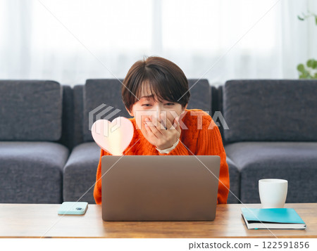 A middle-aged woman watching a live broadcast on her laptop computer A middle-aged woman watching a live broadcast on her laptop computer 122591856
